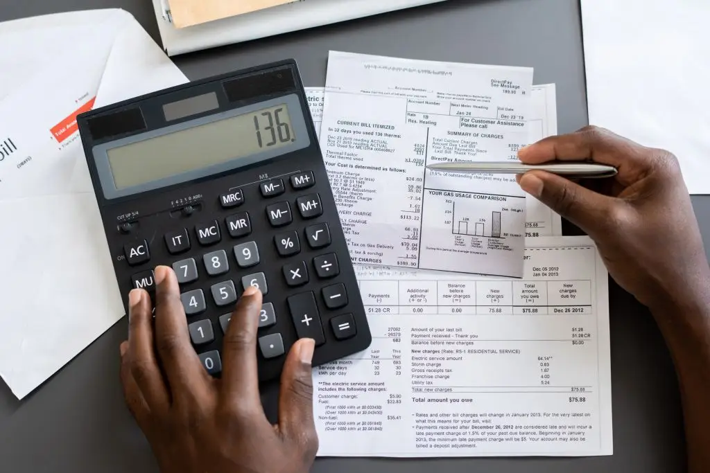 Above view of man checking receipts using calculator at table